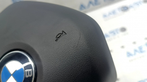 The airbag in the driver's steering wheel of the BMW 3 G20 19-24 is black and scratched.