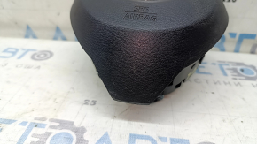 The driver's side airbag in the steering wheel of a Nissan Rogue 17-20 is black, scratched, and has a rusty squib.