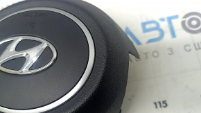 The steering wheel airbag for the driver's side of a Hyundai Tucson 2022-2024 is black and scratched.