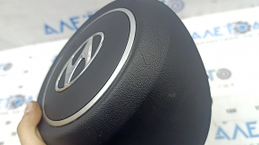 The steering wheel airbag for the driver's side of a Hyundai Tucson 2022-2024 is black and scratched.