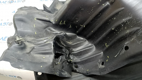 The front left fender liner of a Mazda CX-90 24-26 is dented, torn, and punctured.