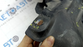The front left fender liner of a Mazda CX-90 24-26 is dented, torn, and punctured.