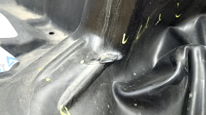 The front left fender liner of a Mazda CX-90 24-26 is dented, torn, and punctured.