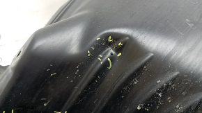 The front left fender liner of a Mazda CX-90 24-26 is dented, torn, and punctured.