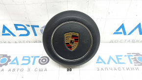 The steering wheel airbag for the driver's side of a Porsche Macan 15-26 is black and scratched.