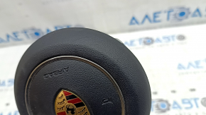 The steering wheel airbag for the driver's side of a Porsche Macan 15-26 is black and scratched.