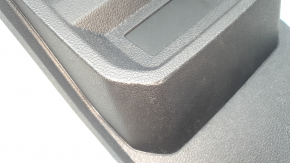 The center console trim with a deflector for a VW Tiguan 20-24 is black, worn, and has scratches.