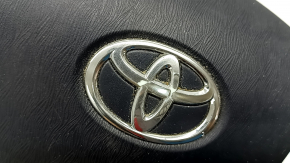 The airbag in the driver's steering wheel of a Toyota Prius 30 10-15 is black, scratched, worn, and the chrome is peeling.