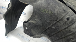 The rear left fender liner of a Kia Sportage 23-26 is dented and torn.
