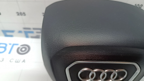 The Audi Q7 2020-2026 driver's steering wheel airbag is black and scratched.