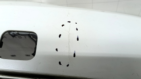 The bare lower rear bumper of a Volvo XC90 16-26 for parking sensors, white, the parking sensor mount is broken, dented, and there are cracks in the mounts.