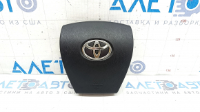 The driver's side airbag in the steering wheel of a Toyota Prius V 12-17 is black and scratched.