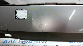 The bare lower rear bumper of a Volvo XC90 16-23, under the parking sensors and moldings, silver, scratches, chips, and blistered paint.