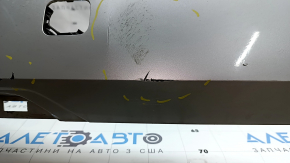 The bare lower rear bumper of a Volvo XC90 16-23, under the parking sensors and moldings, silver, scratches, chips, and blistered paint.