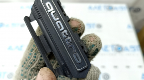 The emblem with the inscription "quattro" on the radiator grille of the Audi A5 F5 20-25 sand