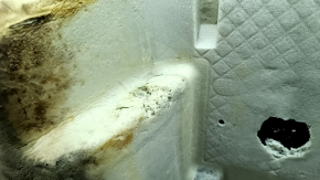 The rear floor covering of a BMW X3 F25 11-17 is black and needs cleaning. The foam rubber is torn and 2 mat fasteners are missing