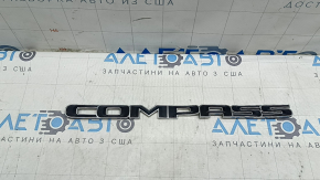 The emblem with the COMPASS inscription on the front right door of the Jeep Compass 17-26 is bent and scratched