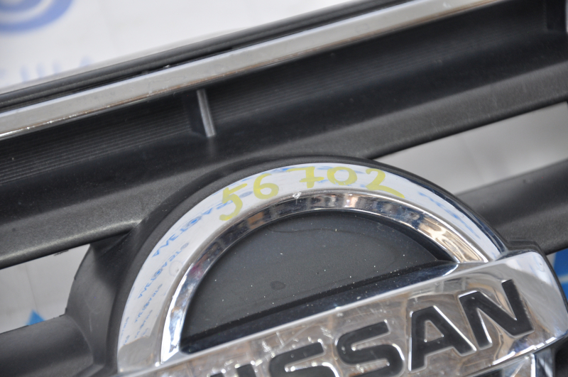 Nissan Alltima 2005 USA radiator grille has chrome breakage, tears, broken fasteners, torn guides, and a bump on the emblem.