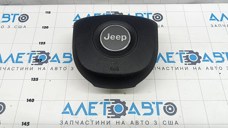 The driver's side airbag in the Jeep Grand Cherokee WK2 14-18 steering wheel is black, scratched, and has a rusty squib.