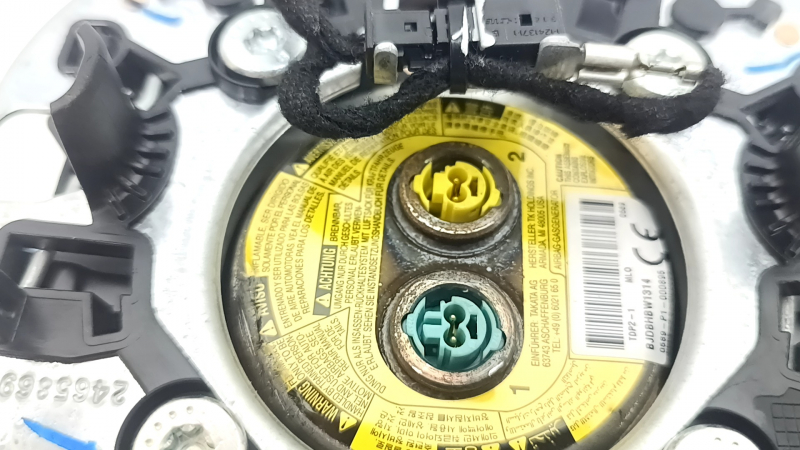 The driver's side airbag in the Jeep Grand Cherokee WK2 14-18 steering wheel is black, scratched, and has a rusty squib.