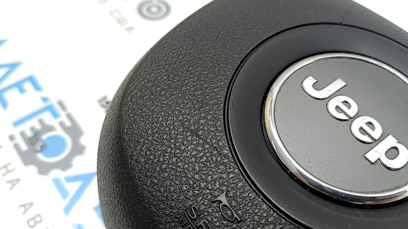 The driver's side airbag in the Jeep Grand Cherokee WK2 14-18 steering wheel is black, scratched, and has a rusty squib.