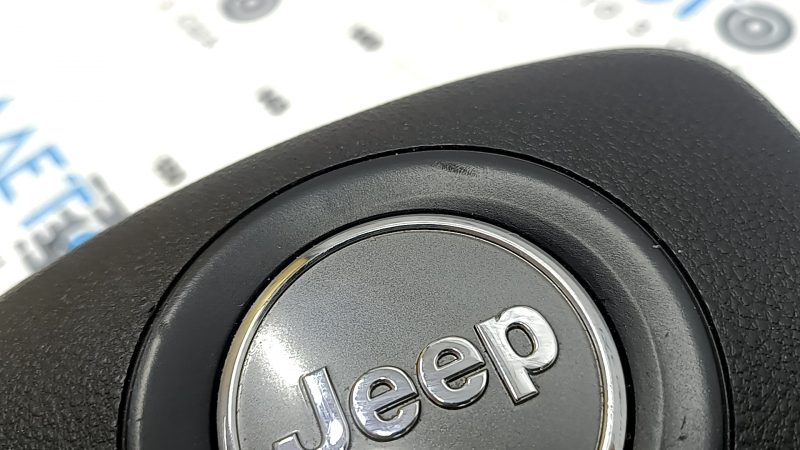 The driver's side airbag in the Jeep Grand Cherokee WK2 14-18 steering wheel is black, scratched, and has a rusty squib.