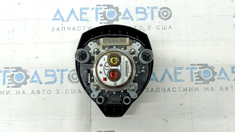 The driver's side steering wheel airbag for a Nissan Rogue 17-20 is black, has scratches, and is rusty.