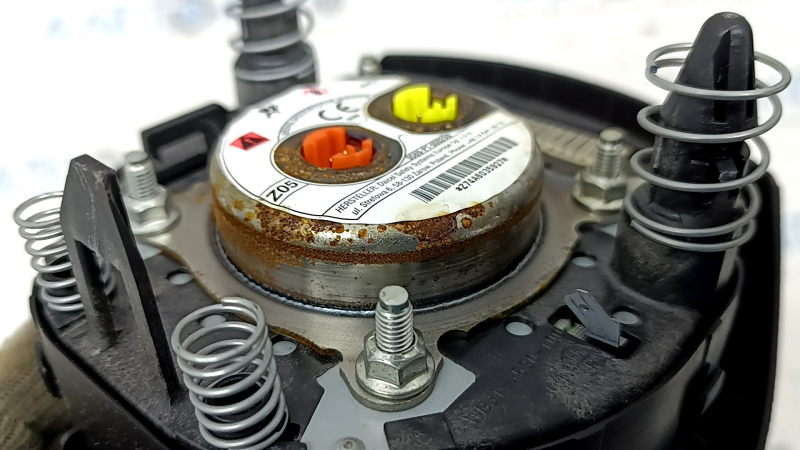 The driver's side steering wheel airbag for a Nissan Rogue 17-20 is black, has scratches, and is rusty.