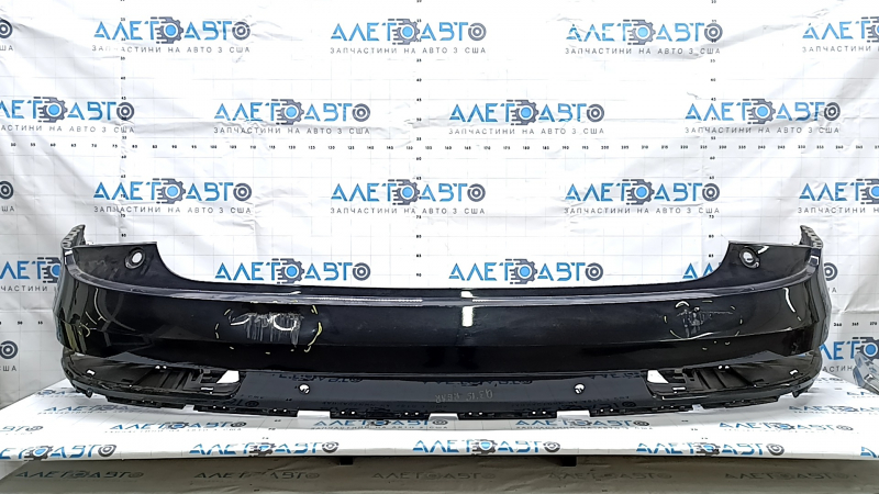 The bare rear bumper, upper part of the Audi Q3 8U 16-18, under 2 parking sensors, is dented, scratched, and cracked.