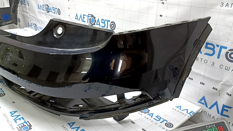 The bare rear bumper, upper part of the Audi Q3 8U 16-18, under 2 parking sensors, is dented, scratched, and cracked.