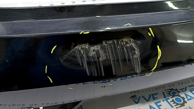 The bare rear bumper, upper part of the Audi Q3 8U 16-18, under 2 parking sensors, is dented, scratched, and cracked.