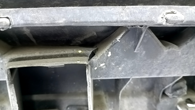 The bare rear bumper, upper part of the Audi Q3 8U 16-18, under 2 parking sensors, is dented, scratched, and cracked.