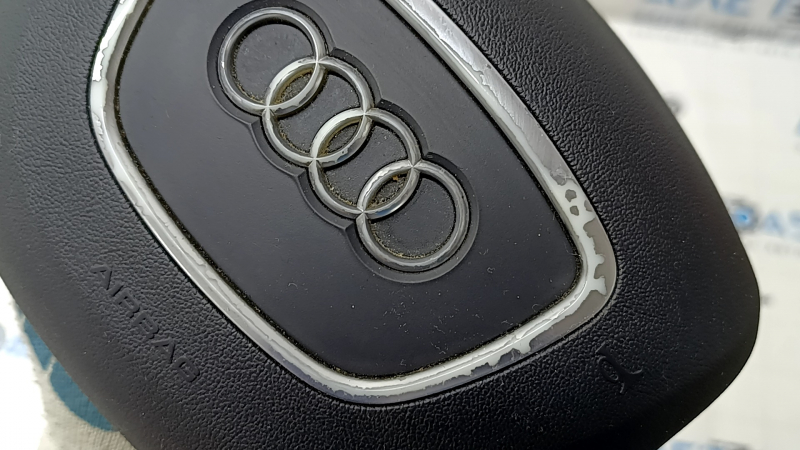 The steering wheel airbag for the driver's side of the Audi Q7 4L 10-15 is black, the chrome is peeling, and there is a scratch.