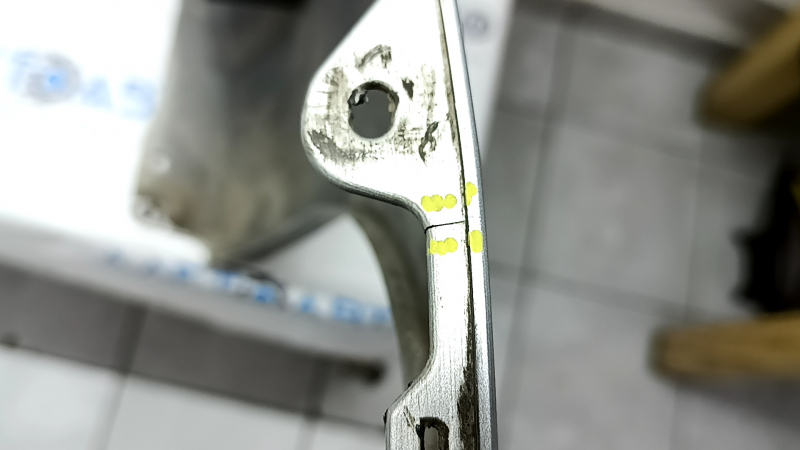 The rear bumper of a Toyota Camry V40 hybrid is bare, silver, pressed, and has cracks.