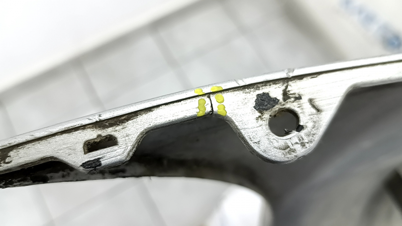 The rear bumper of a Toyota Camry V40 hybrid is bare, silver, pressed, and has cracks.