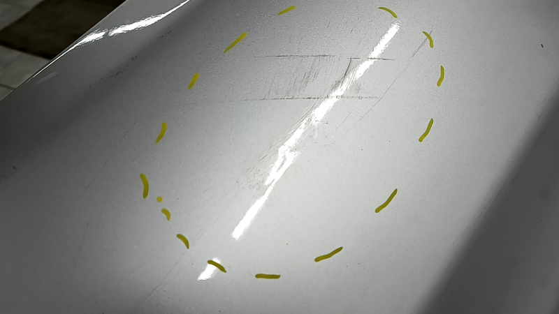 The rear bumper of a Toyota Camry V40 hybrid is bare, silver, pressed, and has cracks.