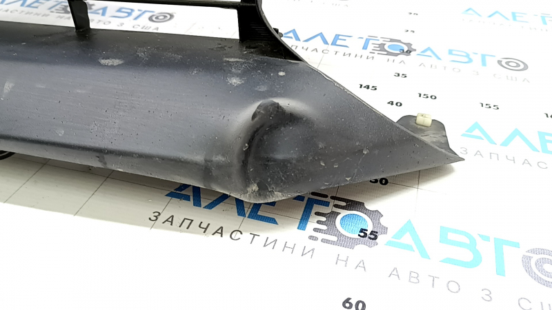 The radiator grill of a Toyota Prius 50 Prime 17-19 under parking sensors is cracked and dented.