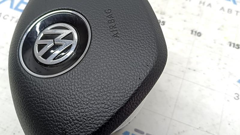 The driver's side airbag in the steering wheel of a VW Tiguan 18-21 is black and scratched.