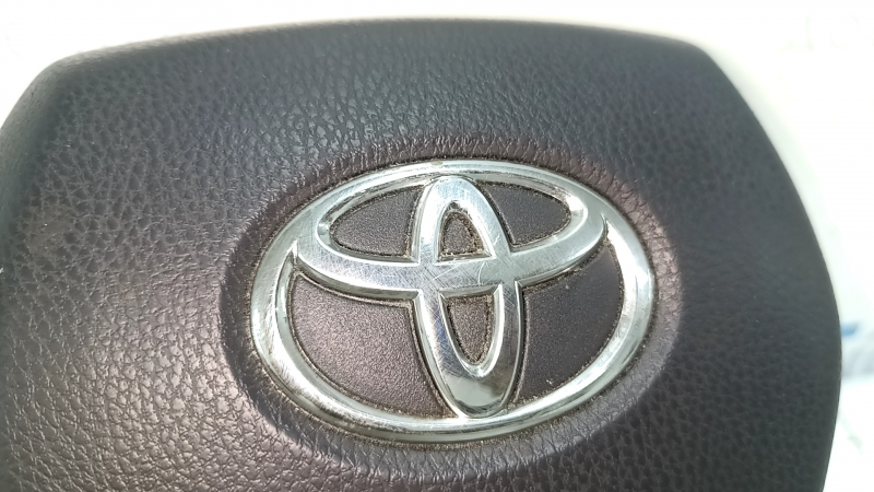 The Toyota Venza 21-24 driver's steering wheel airbag is black and scratched.