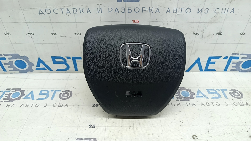 The steering wheel airbag for the driver's side of a 1993 Honda Accord is black and scratched.