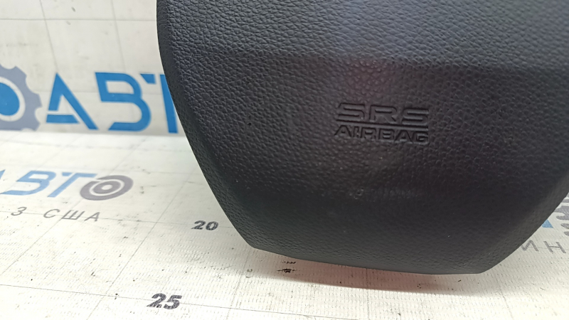 The steering wheel airbag for the driver's side of a 1993 Honda Accord is black and scratched.