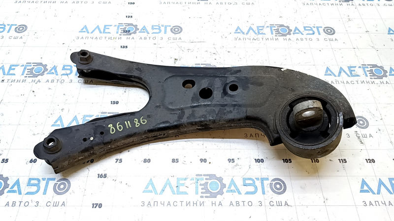 The rear left longitudinal control arm of a Lexus RX350 RX450H 10-15 has a torn silent block and is rusty.