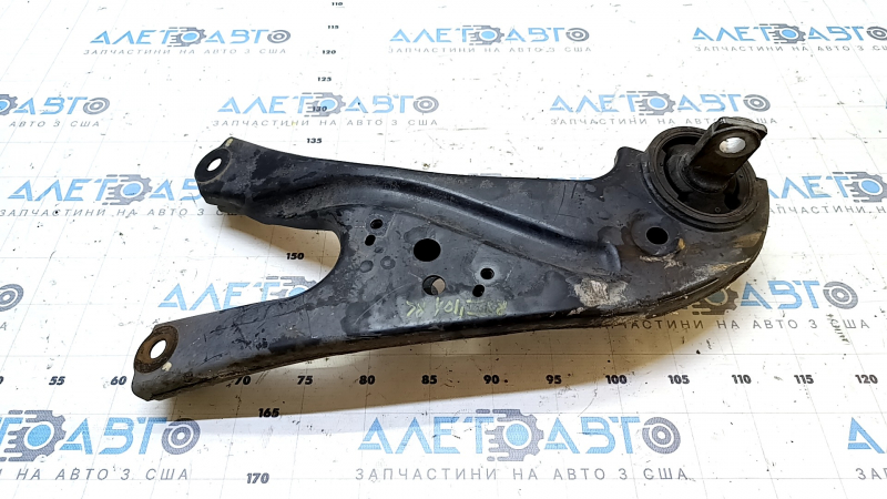 The rear left longitudinal control arm of a Lexus RX350 RX450H 10-15 has a torn silent block and is rusty.