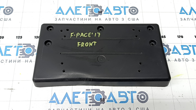 The front license plate plate of a Jaguar F-Pace X761 17-20 Sport is dented and the fasteners are broken.