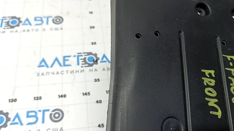 The front license plate plate of a Jaguar F-Pace X761 17-20 Sport is dented and the fasteners are broken.