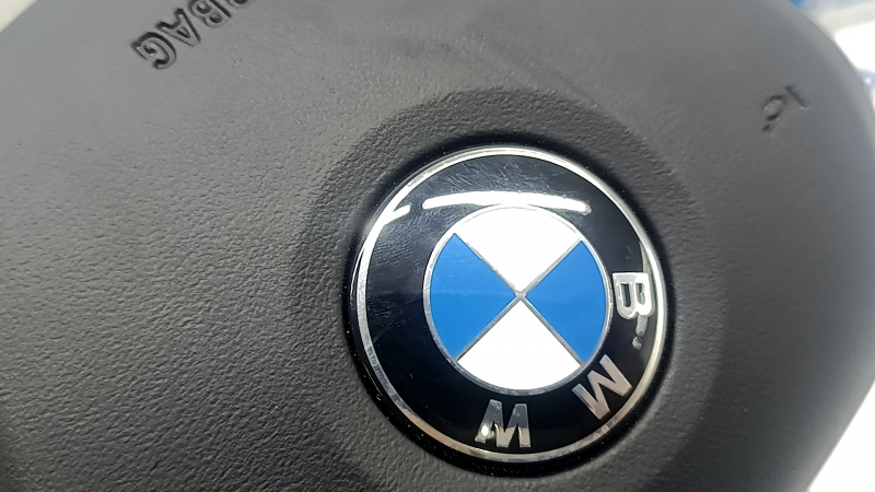 The airbag in the driver's steering wheel of the BMW 3 G20 19-24 is black and scratched.