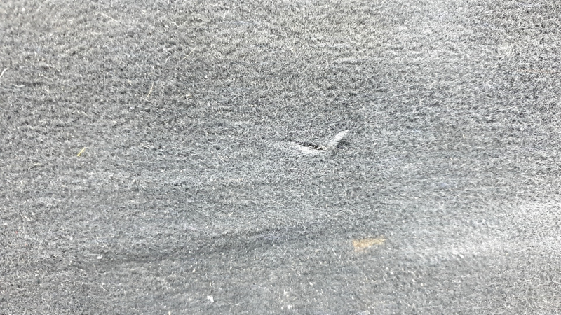The trunk floor of a Ford Explorer 20-25 is black, worn, scratches on the handle, and a tear.