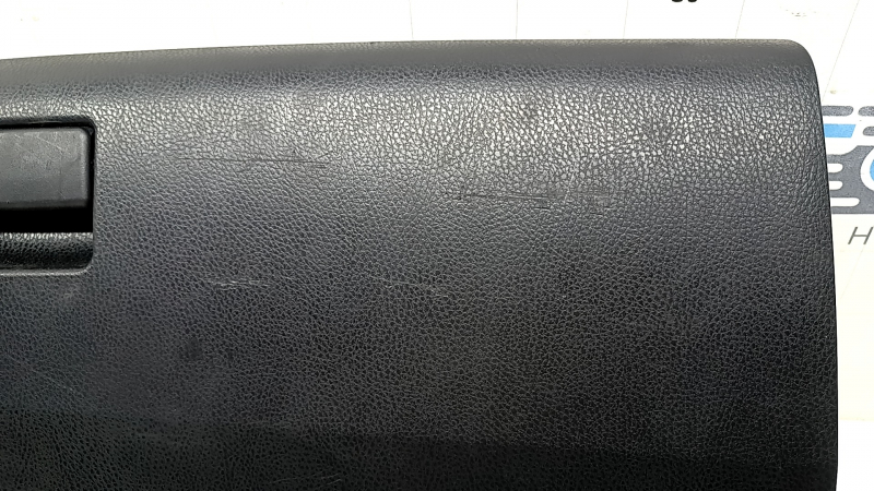 The glove compartment of a Toyota Rav4 2013-2018 is black and has scratches.