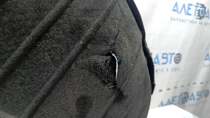 The rear left fender liner of a Kia Sportage 23-26 is dented and torn.