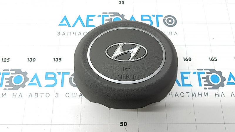 The steering wheel airbag for the driver's side of the Hyundai Elantra 21-26 is dark gray.